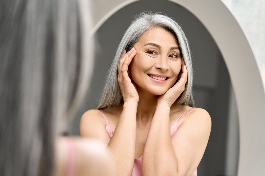 woman with gray hair looking at mirror reflection