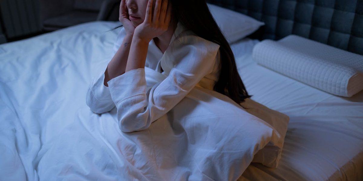 Woman in White Long Sleeve Shirt Sitting on a Bed