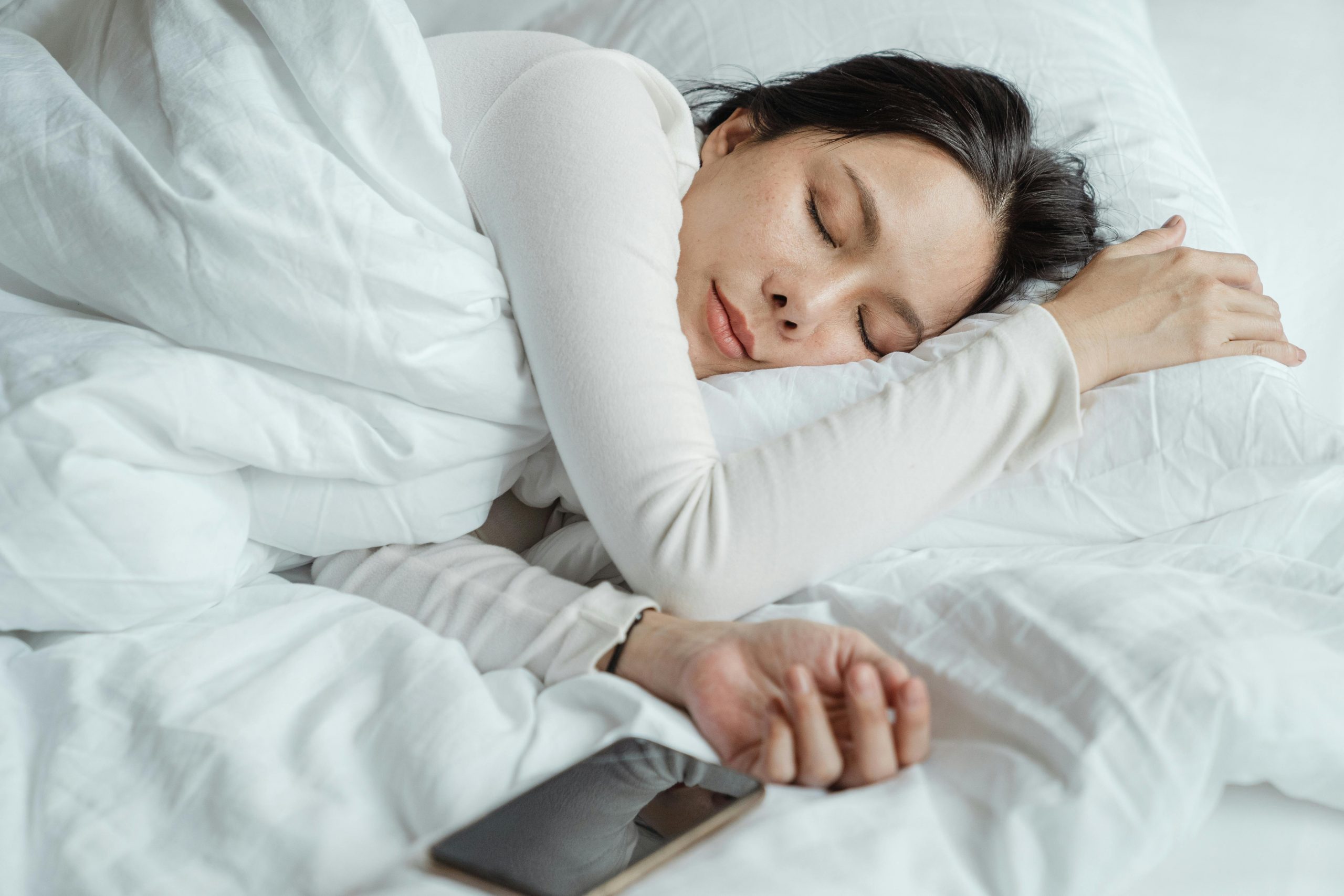 woman sleeping in bed, next to her smartphone
